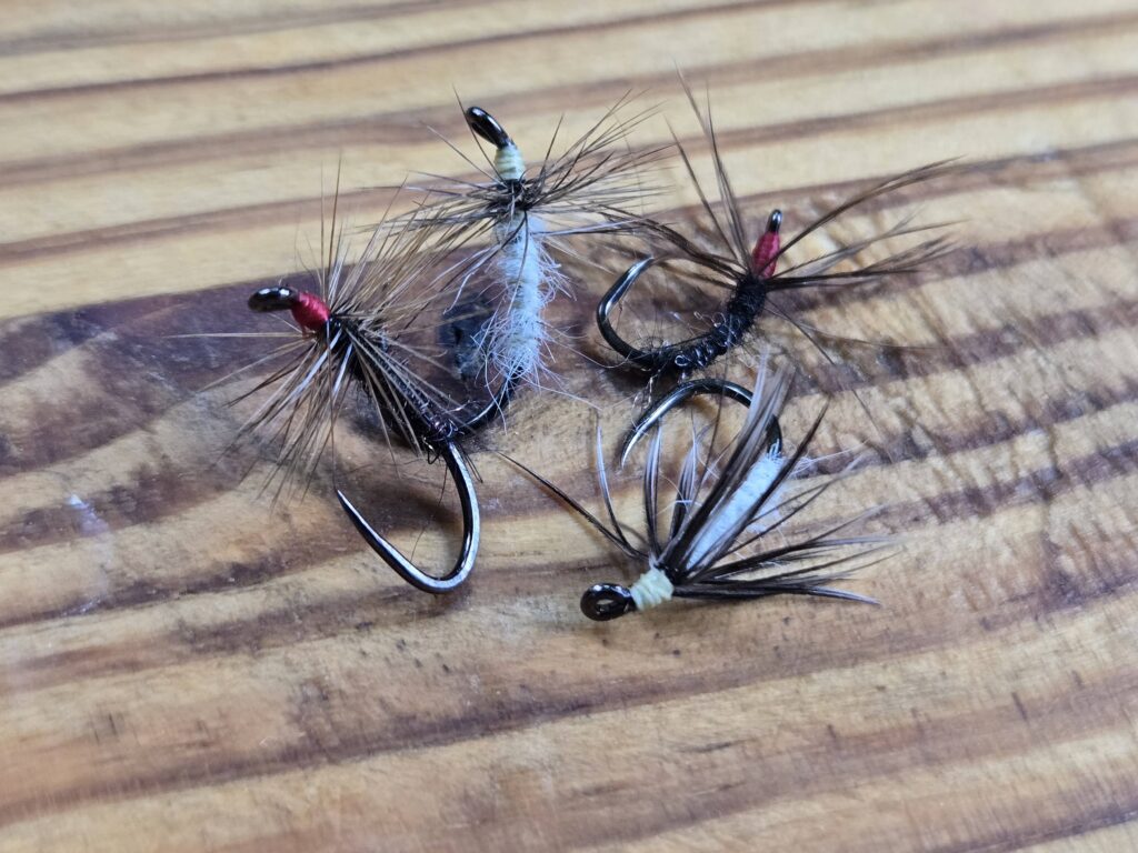 Four fishing flies on a wooden surface