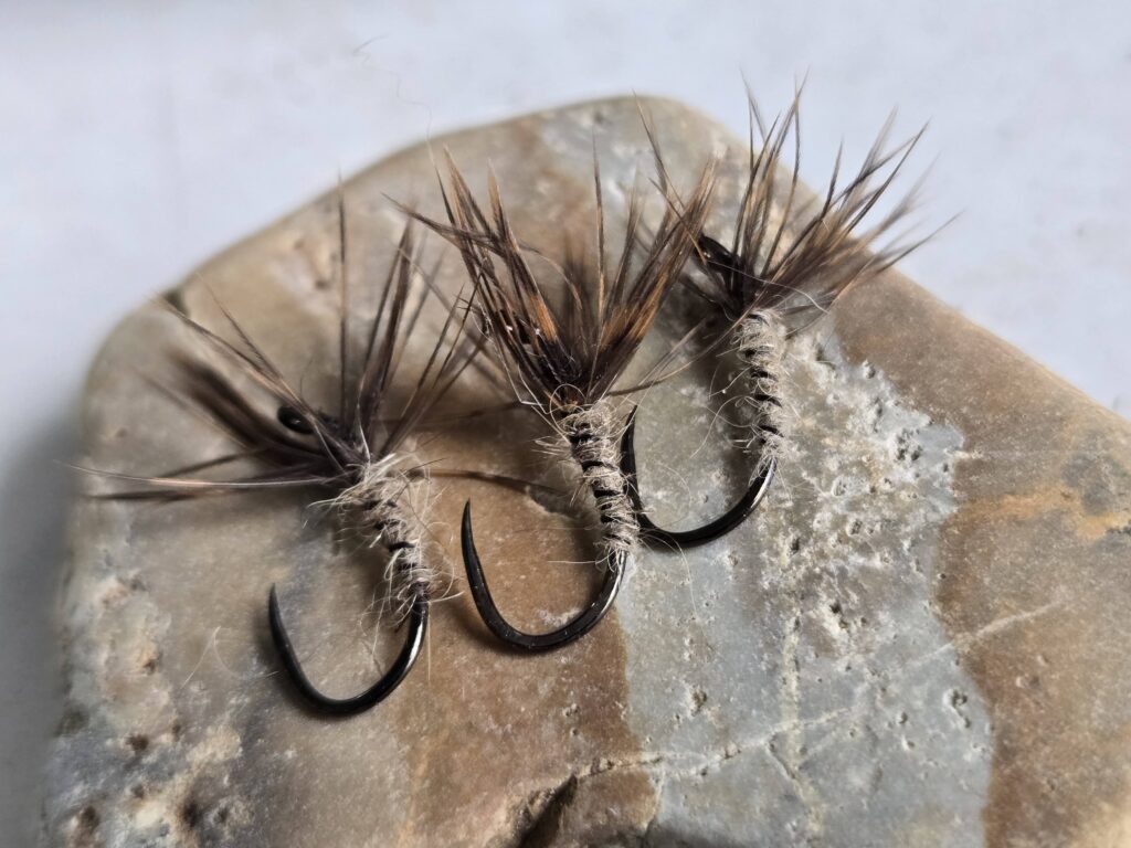 Three fishing flies on a stone